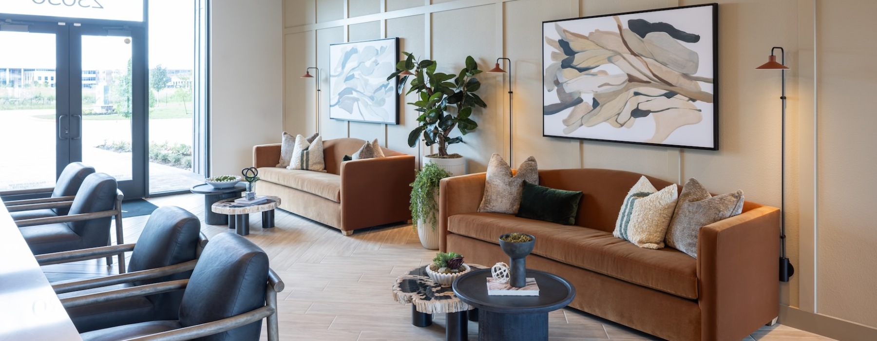 leasing office with two brown couches and two leasing desks with leather seating