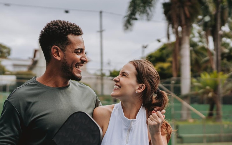 a man and woman holding tennis rackets and a ball